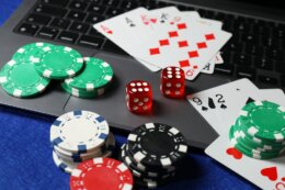 Poker,Chips,,Laptop,,Playing,Cards,And,Dices,On,Blue,Table.